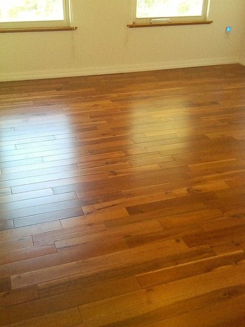 Polished hardwood floor reflecting light in an empty room with two windows.