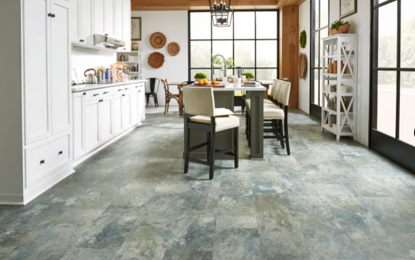 Kitchen with white cabinets, table with chairs, and blue and gray flooring.