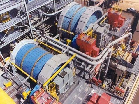 Grandes molinos de bolas industriales, azules y grises, en una estructura metálica en un yacimiento minero.