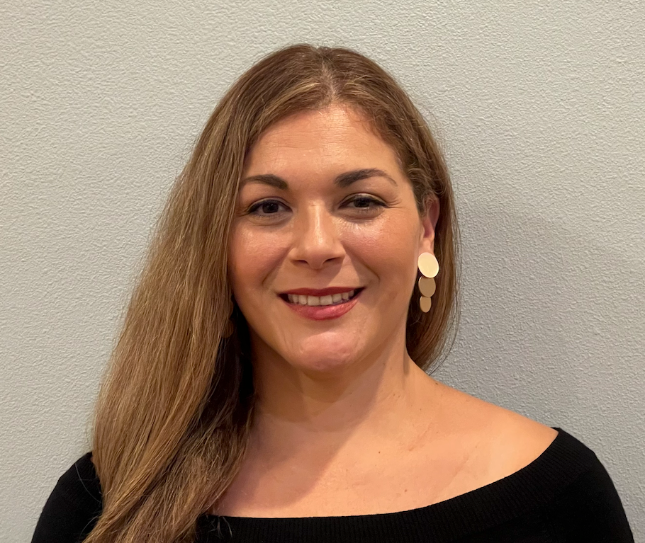 A woman with long hair and earrings is smiling for the camera.