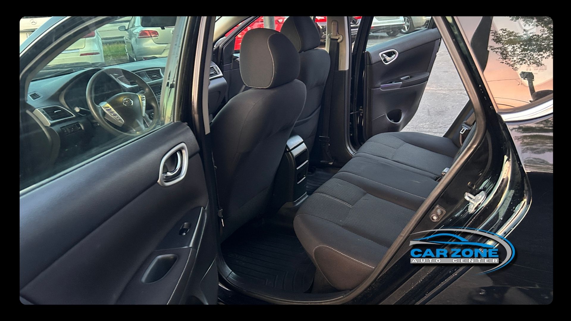 Car interior with rear seats folded down, showing black upholstery and open doors