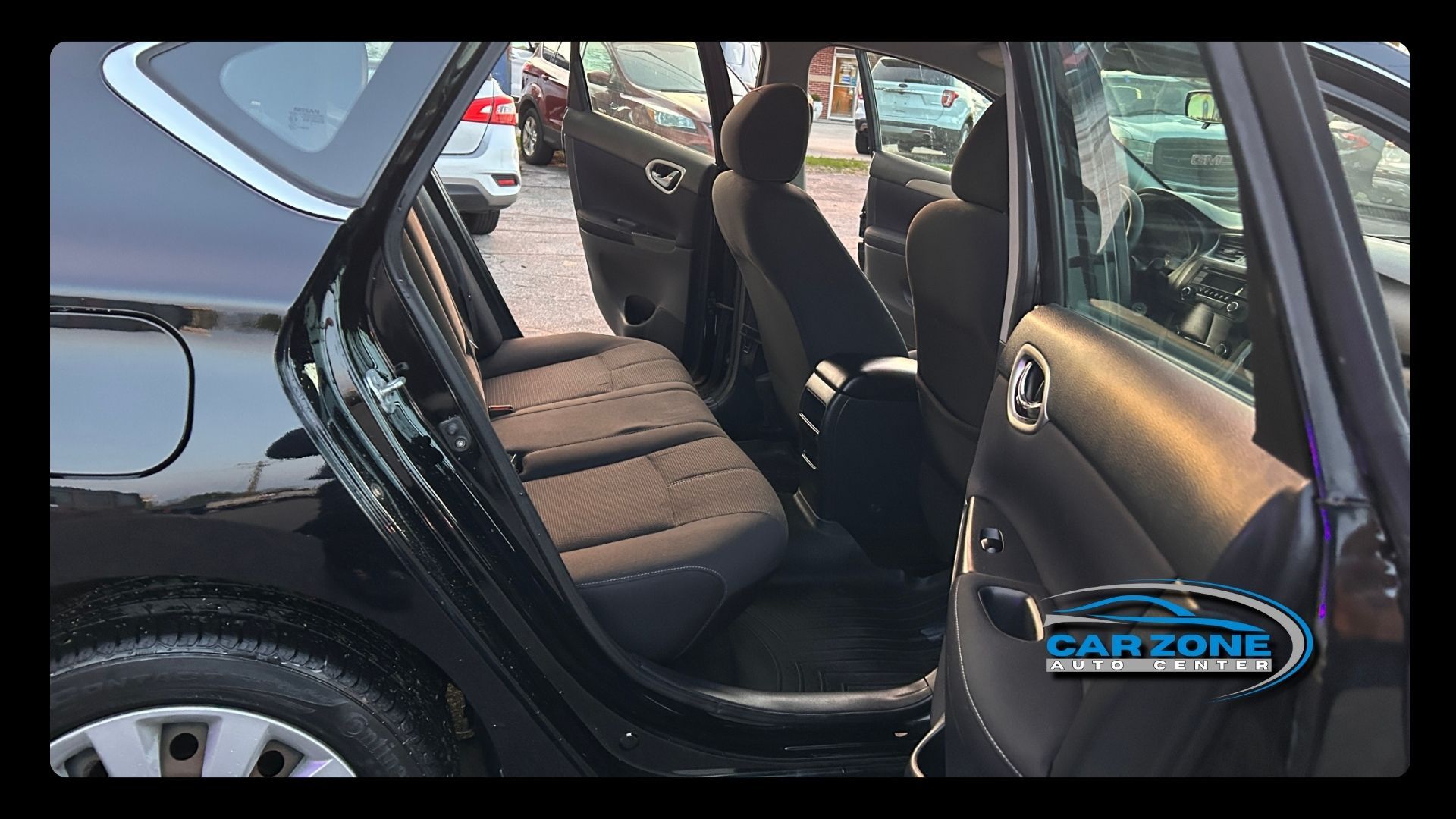 Open car door revealing brown cloth seats and black interior, with a car seat label on the door frame