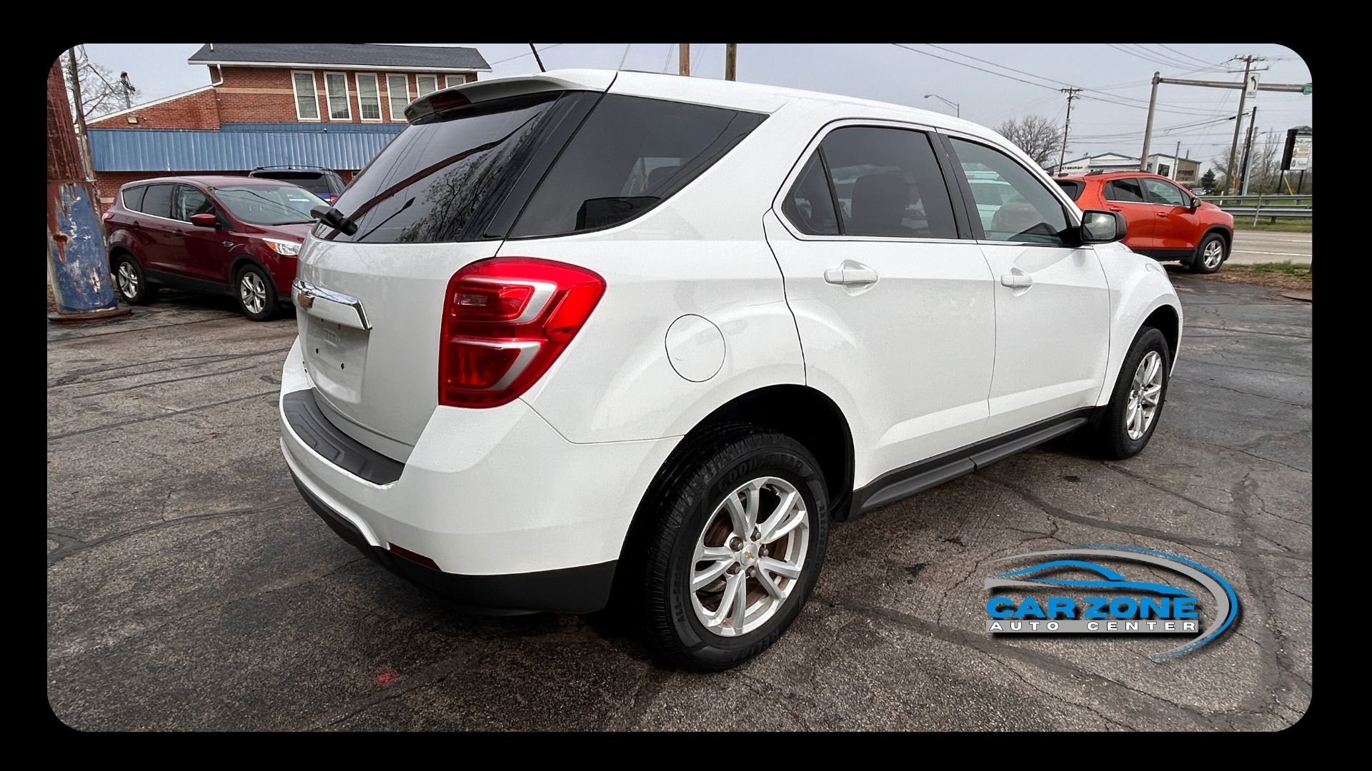 White compact SUV parked on a gravel lot, rear three-quarter view.