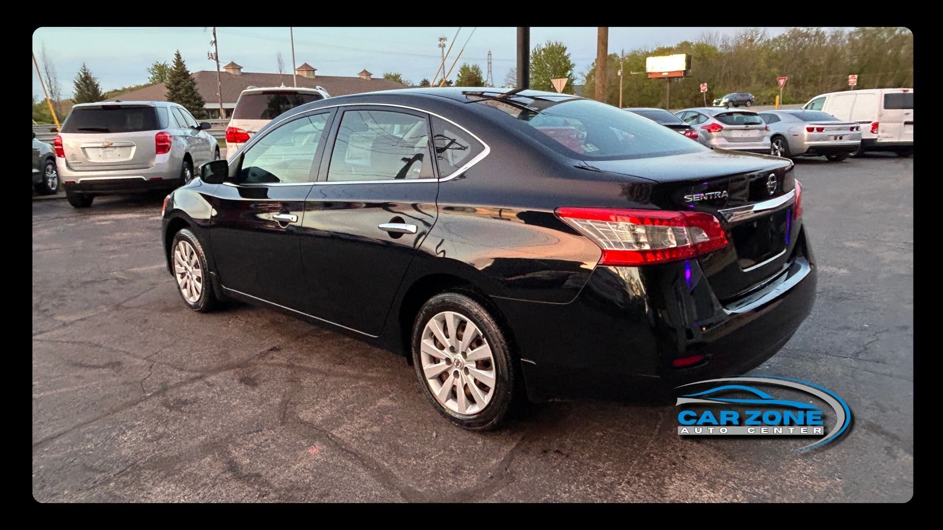 Black sedan parked in a lot, rear side view with dealership sticker visible.
