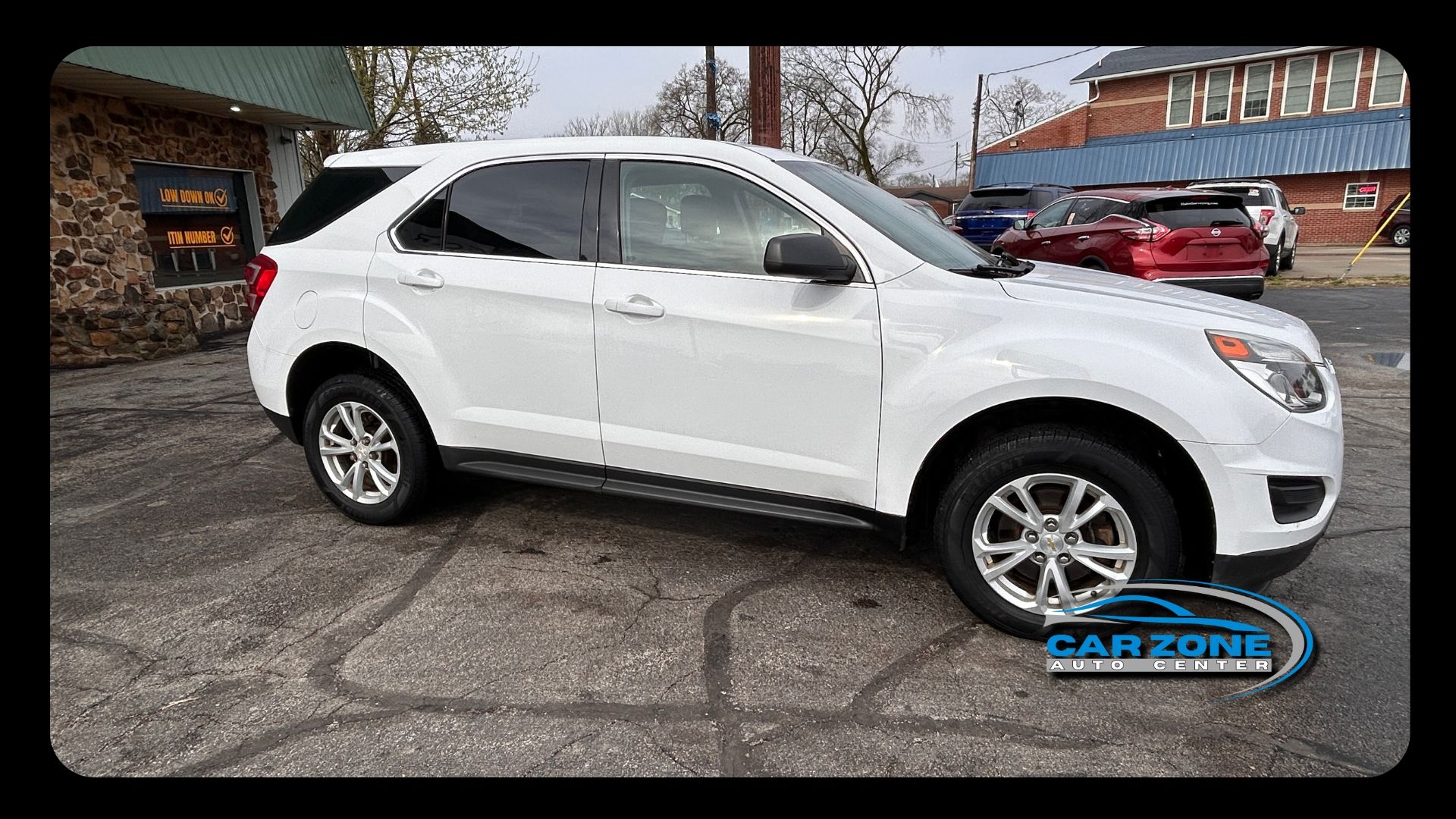 White SUV parked on a street outside a building, side view.