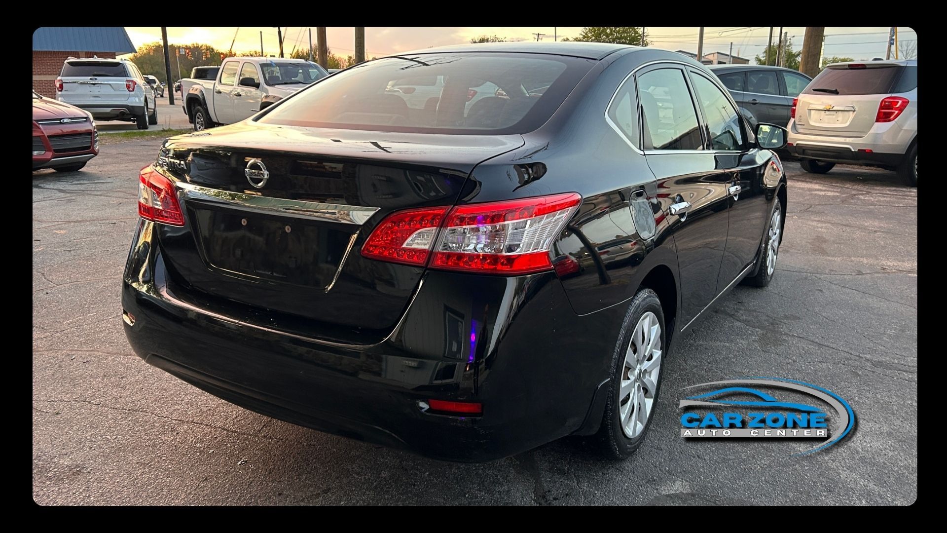 Black Toyota sedan parked in a lot, rear three-quarter view with dealership watermark.