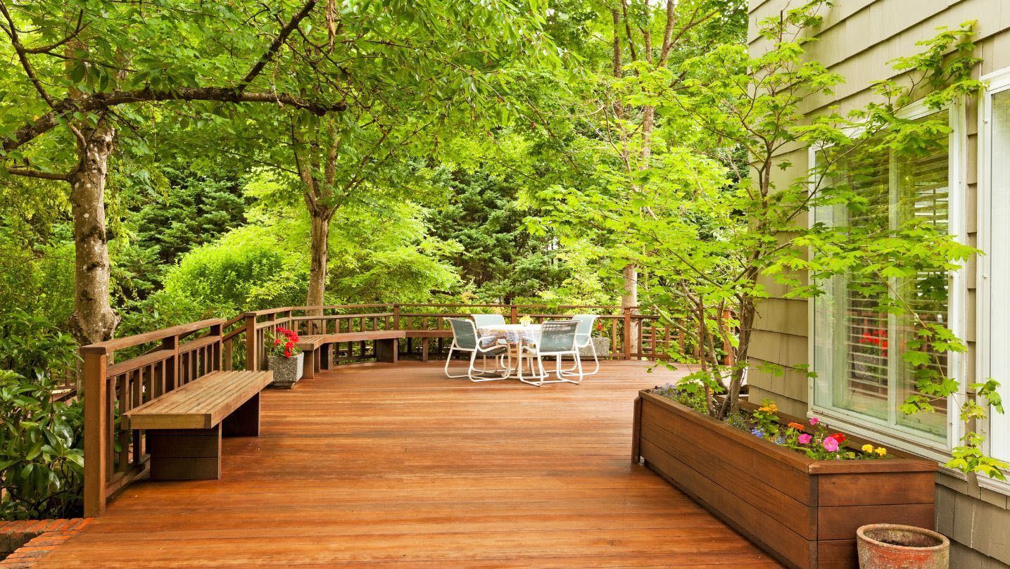 There is a wooden deck with a table and chairs on it.