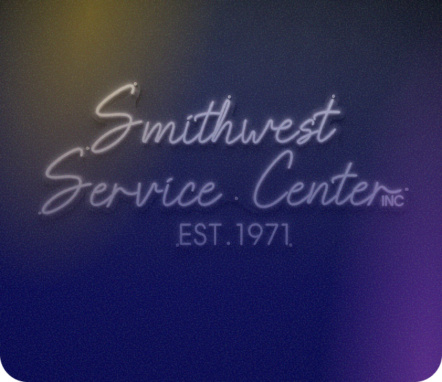 The interior of a service center lobby with a dark service desk, an aquarium, and various automotive brand signage on walls. | Smithwest Service Center