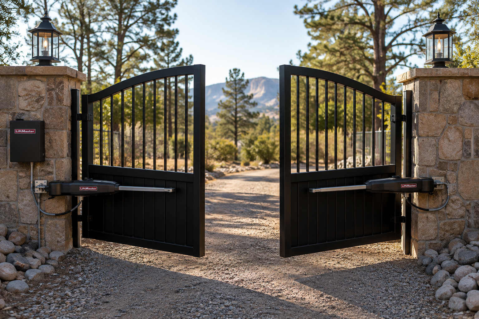 Open black metal gates between stone pillars at a gravel driveway entrance.