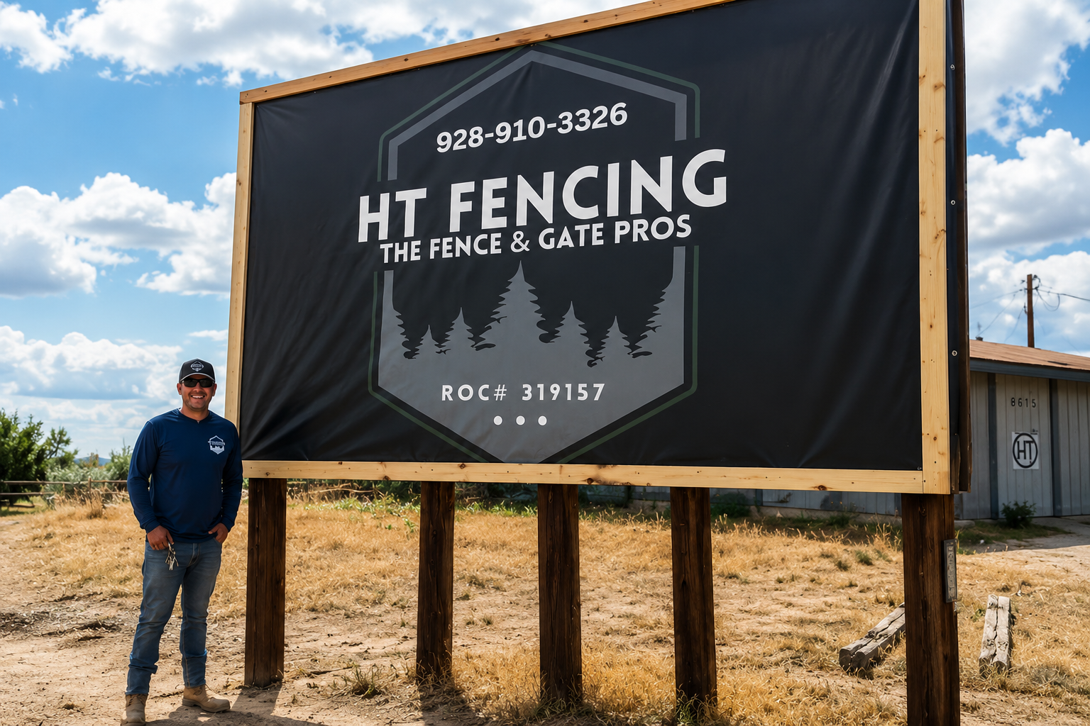 Man standing beside large HT Fencing billboard in a dry field under a blue sky