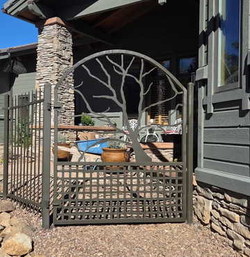 Patio gate with circular tree design beside a stone-and-gray house entryway