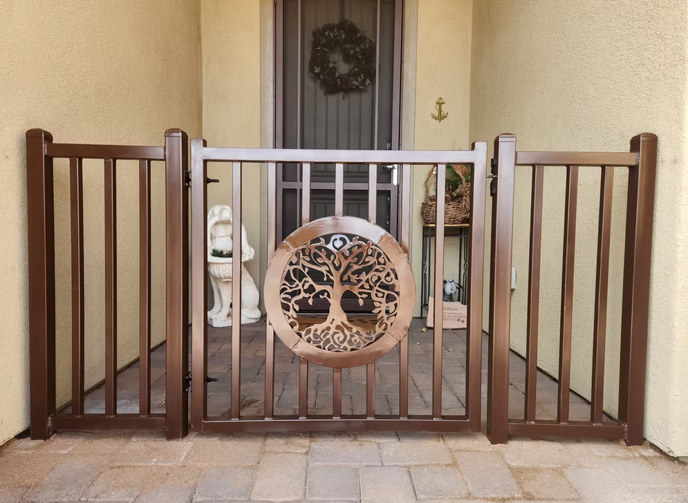 Wooden baby gate with a circular tree emblem blocking a porch entrance