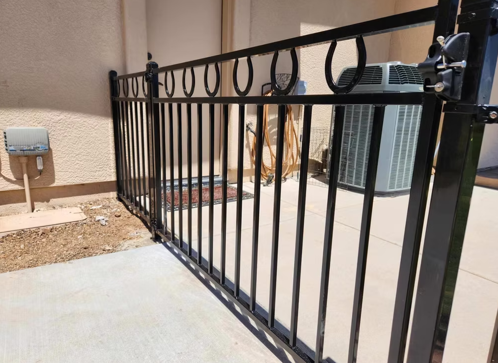 Black metal patio gate beside an air conditioner on a concrete porch