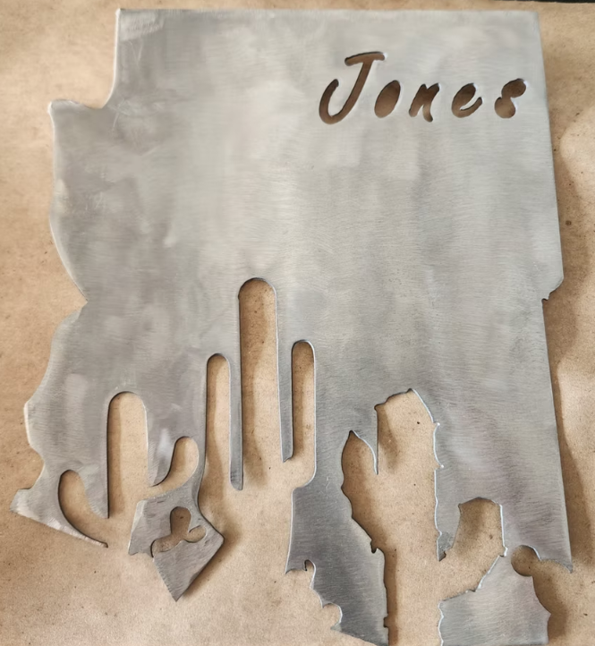 Gray metal sign with “Jones” cutout text and cactus-shaped openings at the bottom.