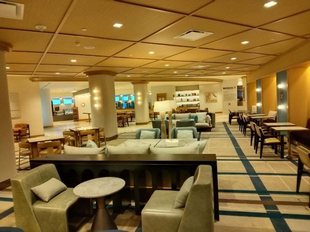 Modern hotel lobby with beige sofas, round tables, and warm ceiling lights