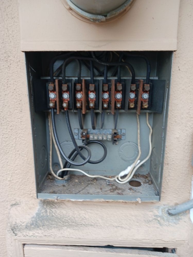 Open electrical panel with exposed breakers and wiring in a wall recess