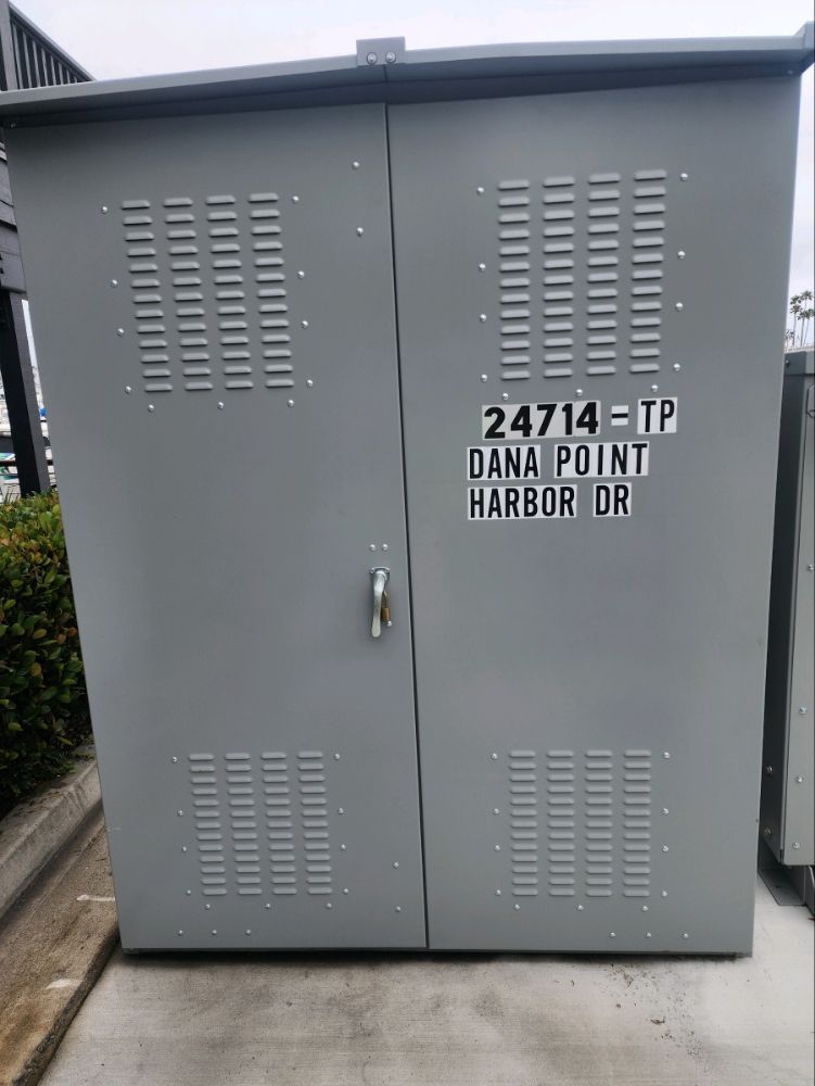 Gray utility cabinet with vented doors and label reading “24714-1P Dana Point Harbor DR”
