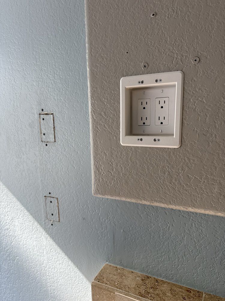 Wall with two outlet boxes and a white electrical outlet plate on a beige panel.