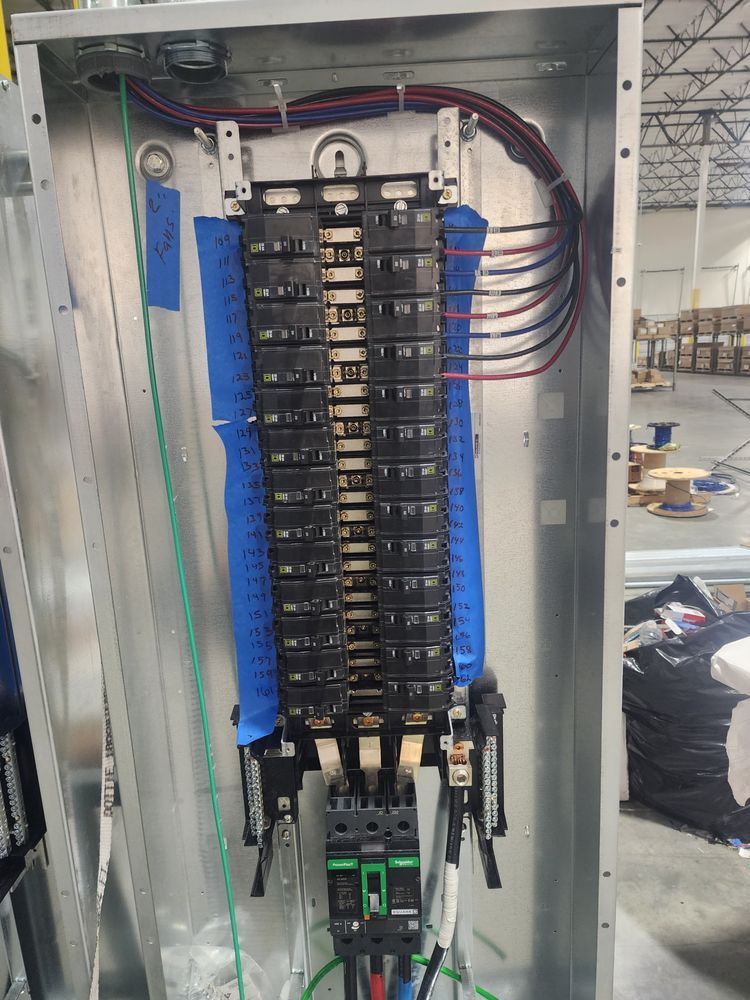 Open electrical control panel with rows of breakers and colored wiring in a metal cabinet