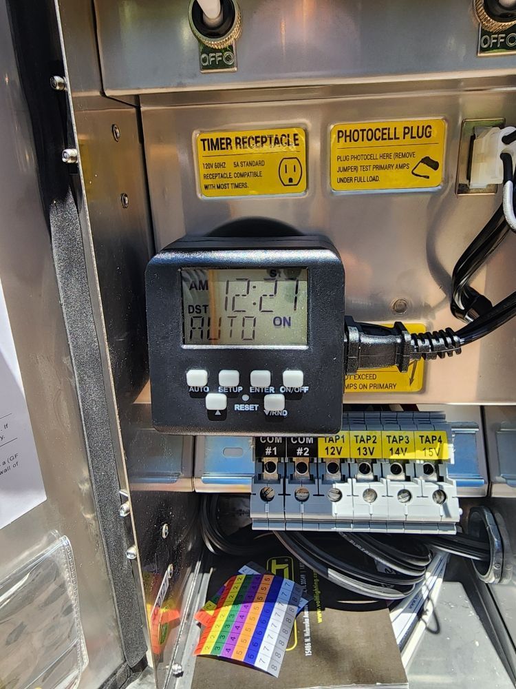 Electrical control panel with timer display, buttons, wiring, and labeled switches inside a metal cabinet