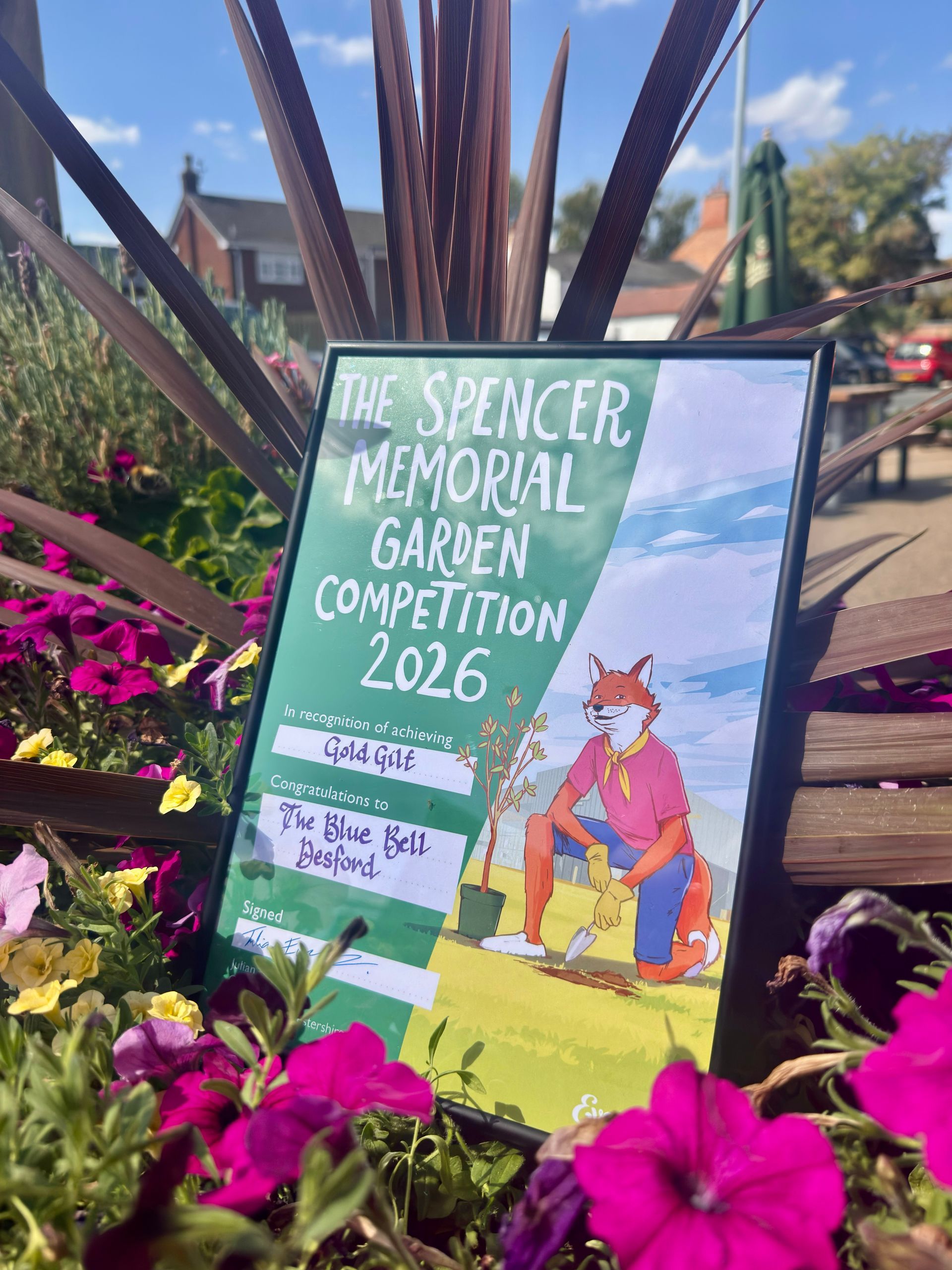 Poster for the Spencer Memorial Garden Competition 2026 among colorful flowers and plants.