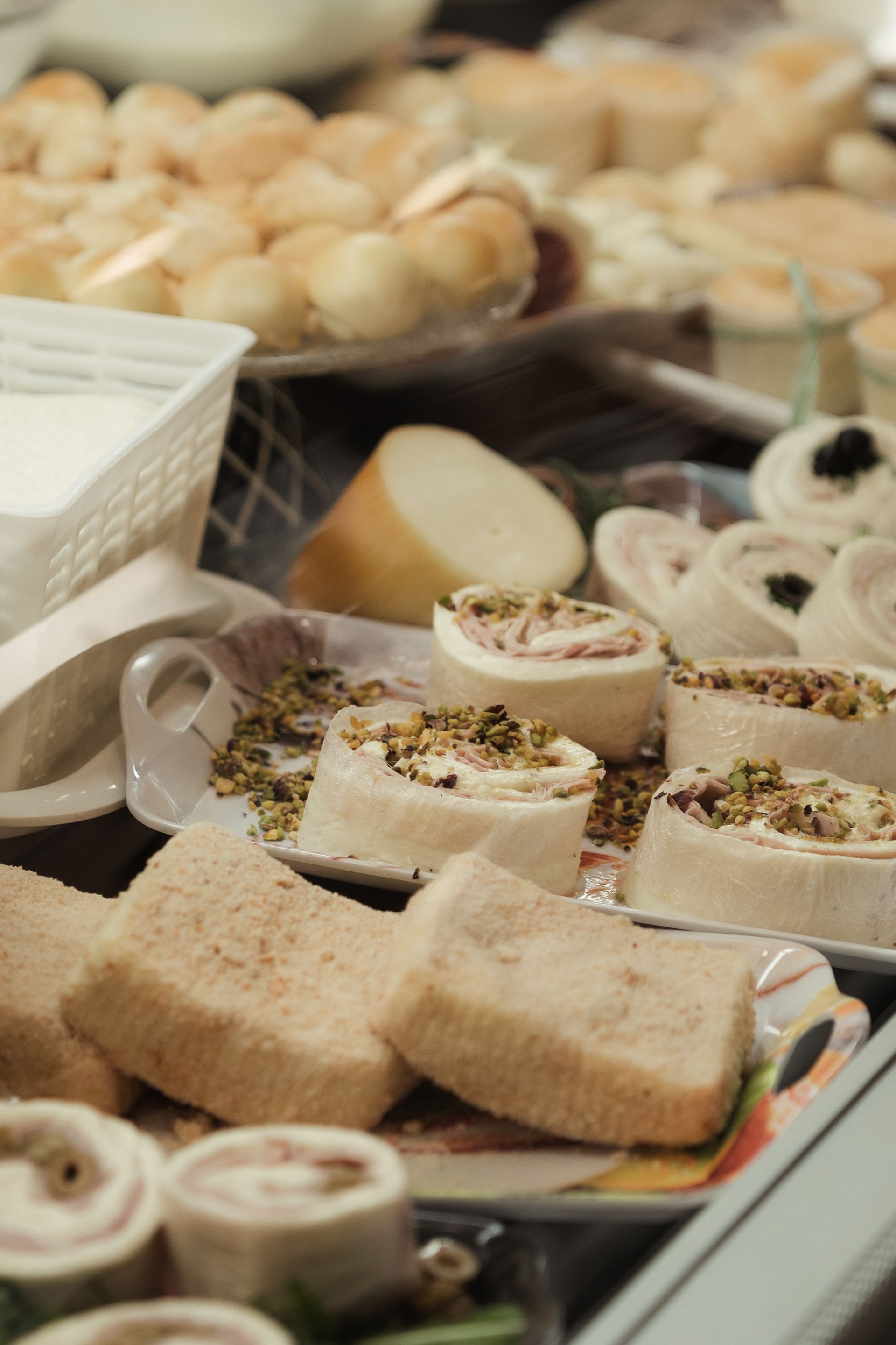 Assortimento di pasticcini a fette e dolci arrotolati esposti su vassoi in una vetrina da pasticceria.