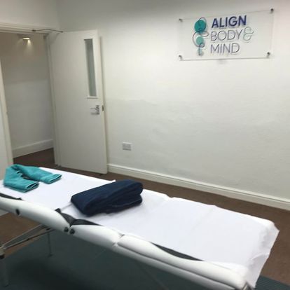 A massage table in a room with a sign that says align body & mind