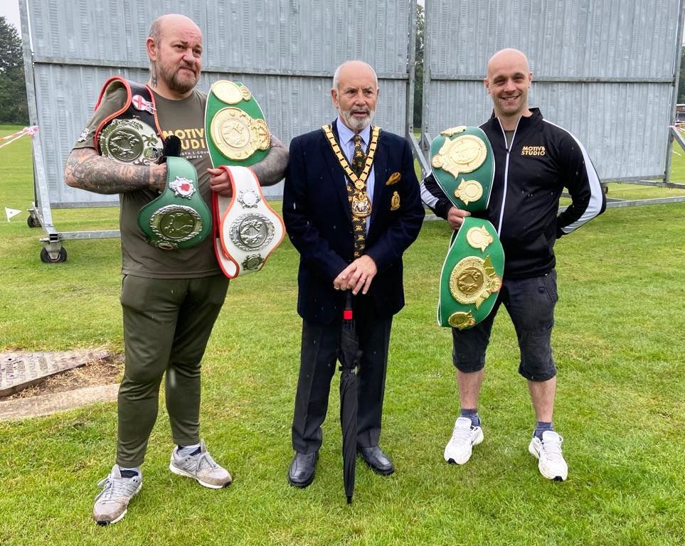 Three men are standing next to each other holding boxing belts.