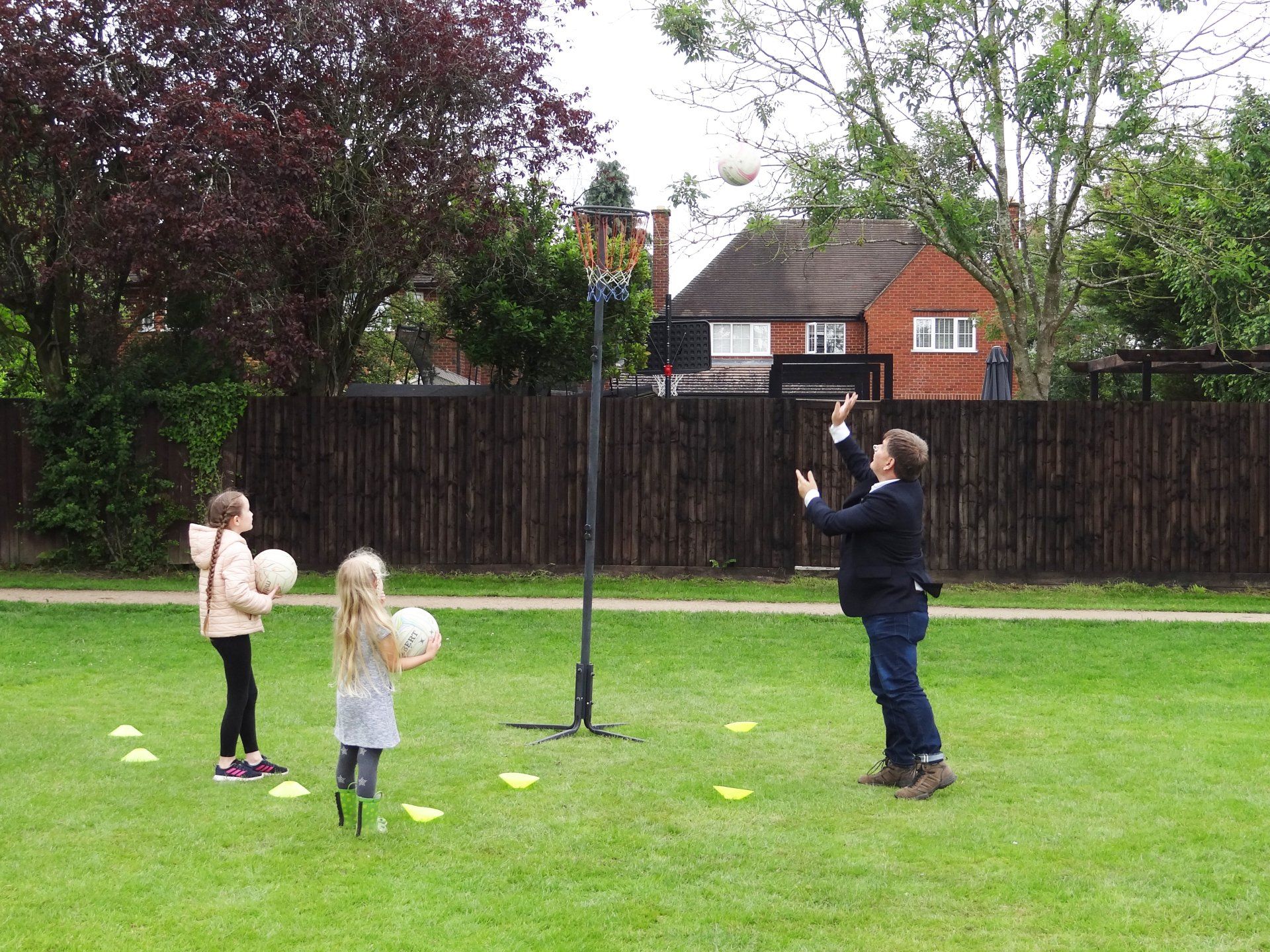 A man and two girls are playing basketball in a park.