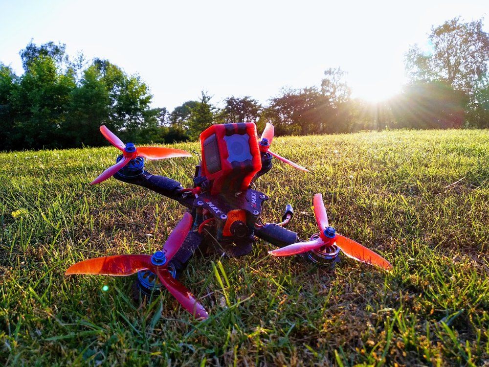 A drone is sitting on top of a lush green field.