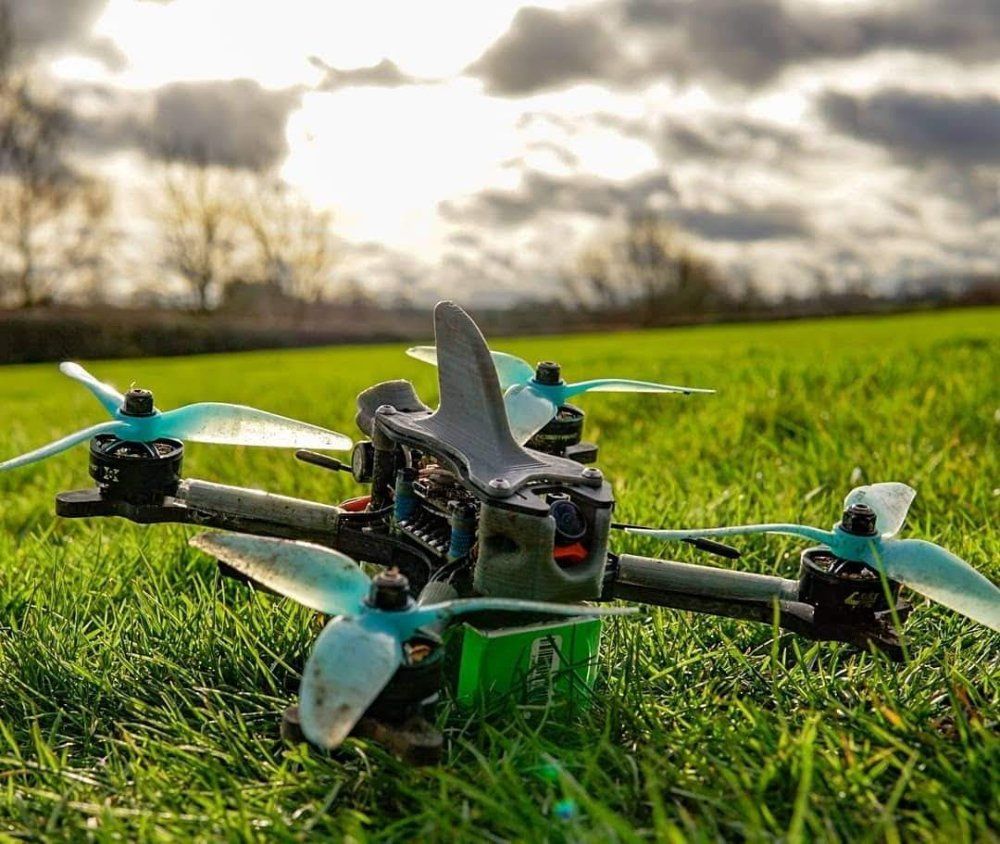 A drone is sitting in the grass in a field.