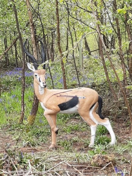 A statue of a gazelle standing in the middle of a forest.