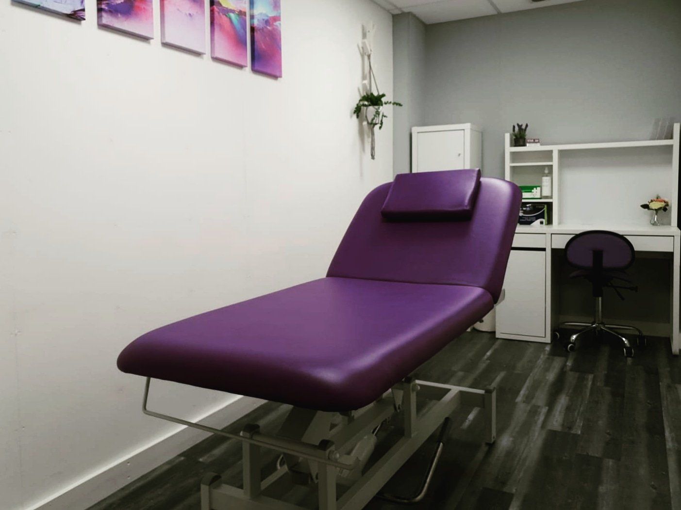 A purple couch is in a room with a desk and chair.