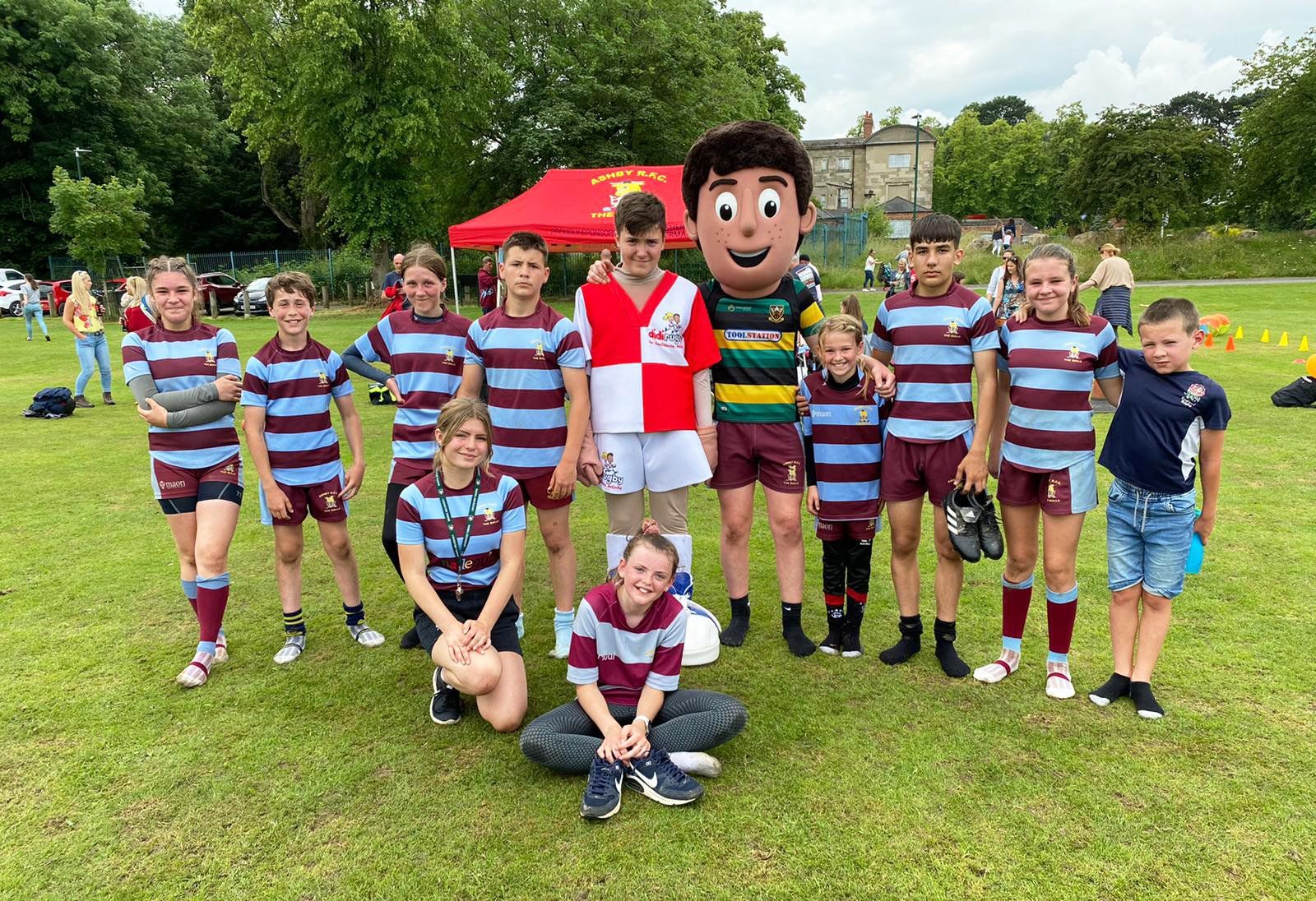 A group of children are posing for a picture with a mascot on a field.