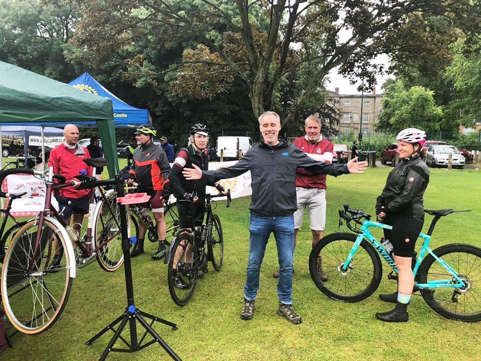 A group of people standing next to bicycles in a park.