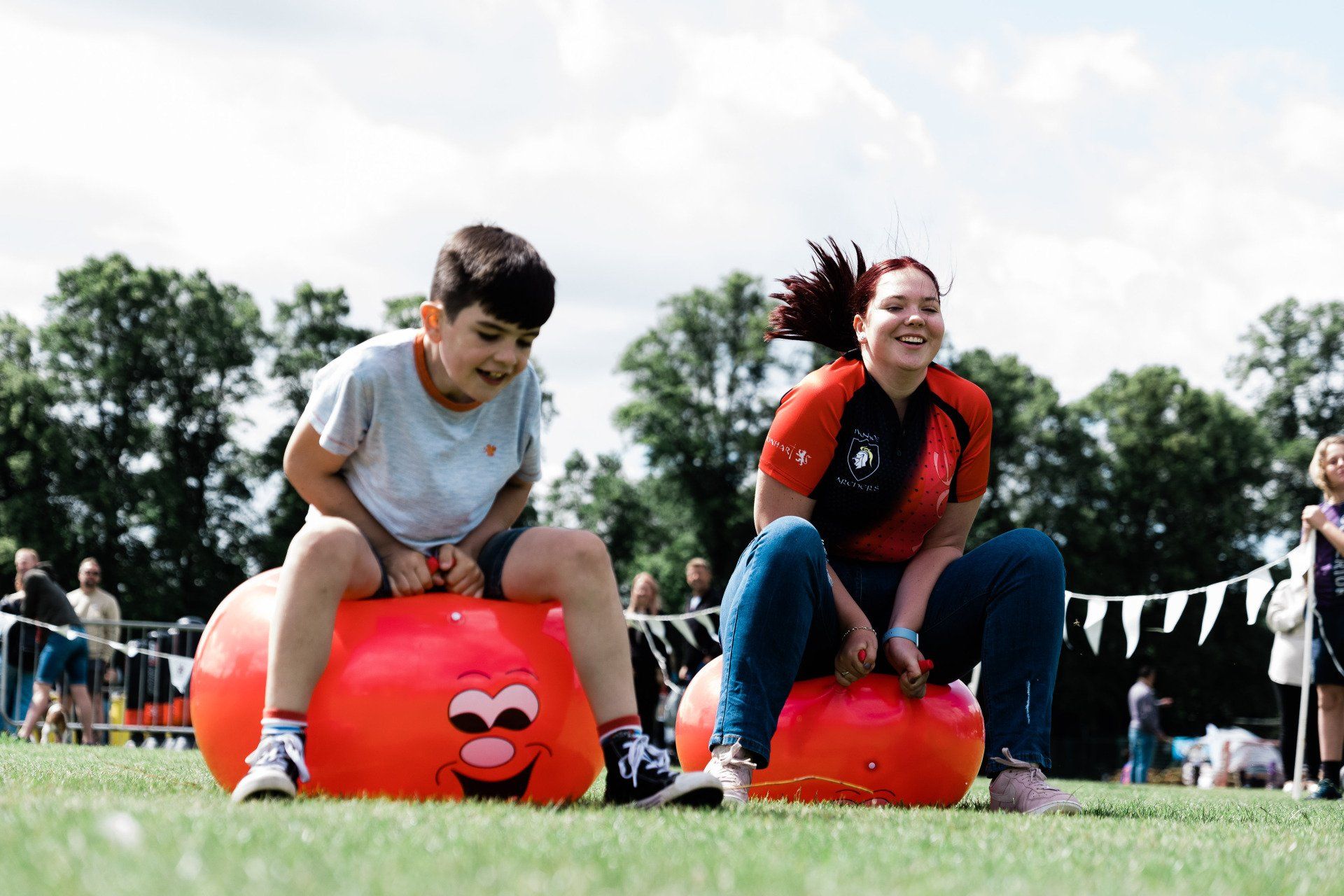 A boy and a woman are sitting on a hopper ball in a field.