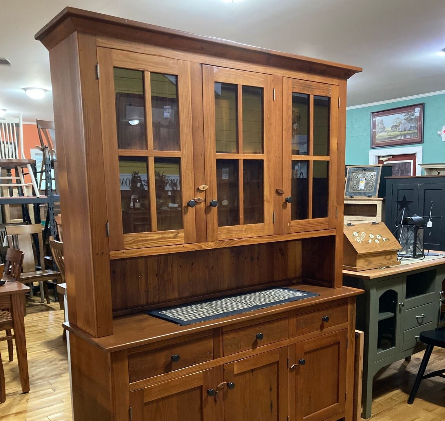 A large wooden cabinet with glass doors and drawers in a room.
