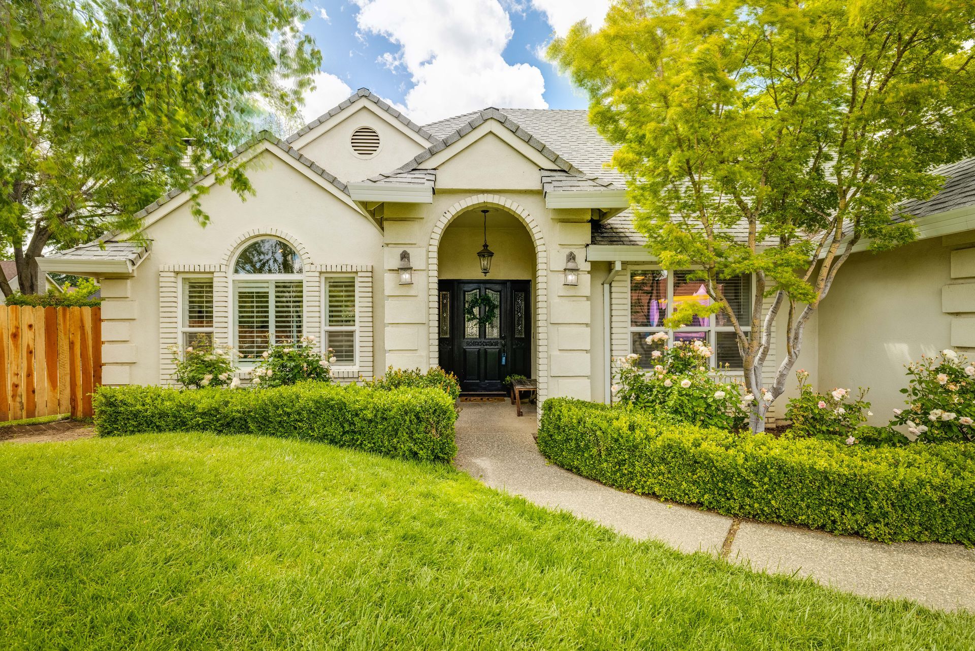 Home with arched entry and manicured front lawn