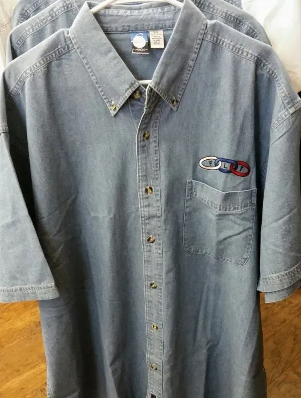 A blue denim shirt is hanging on a hanger.