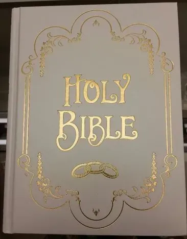 A white holy bible with gold lettering on the cover