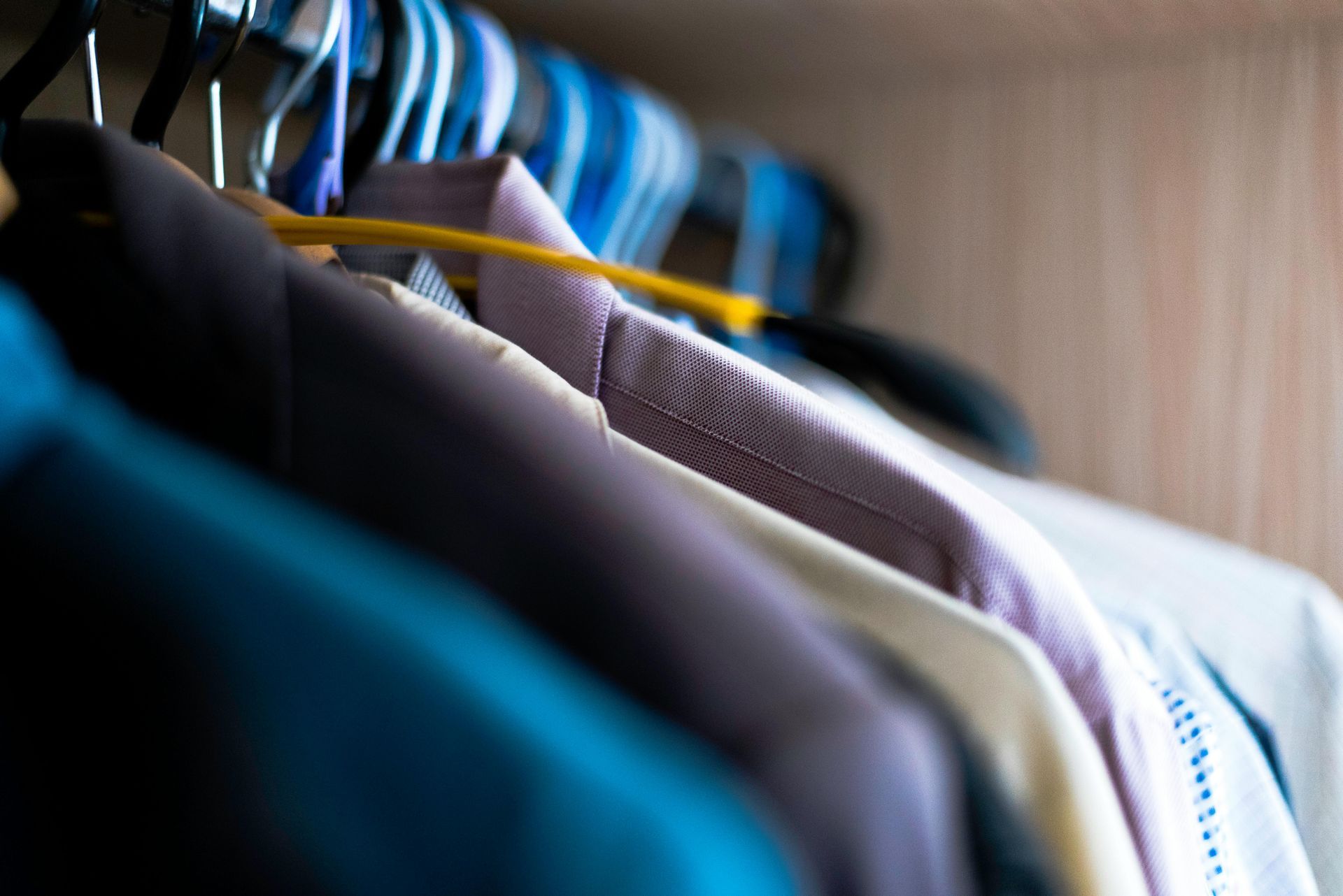 A close up of a closet filled with clothes hanging on hangers.