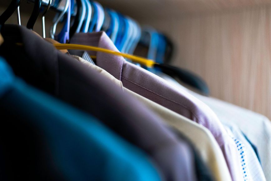 A close up of a closet filled with clothes hanging on hangers.