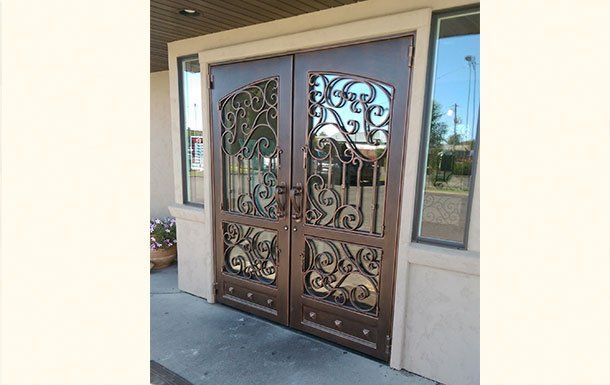 A pair of wrought iron doors on the side of a building.