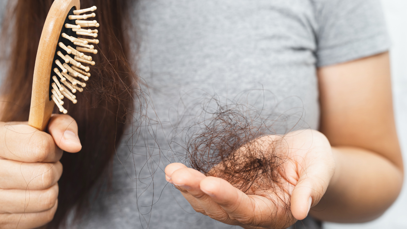 Person holding a hairbrush and a clump of hair in their hand