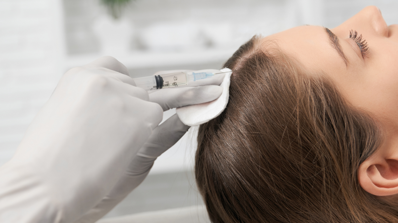 A medical professional administering an injection into a woman's scalp.