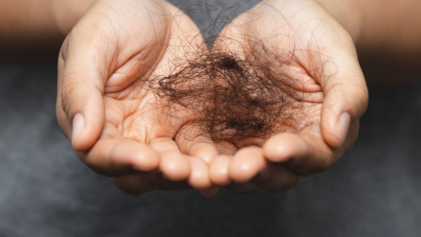 Hands cupping a clump of dark hair against a blurred dark background