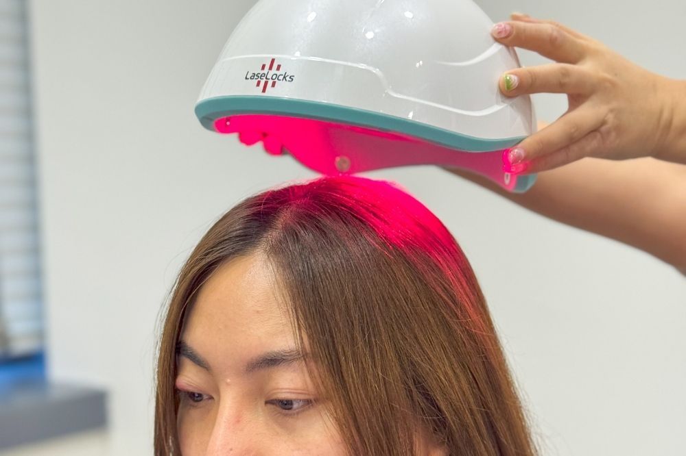 Hair treatment cap with pink UV light over a person's head in a salon