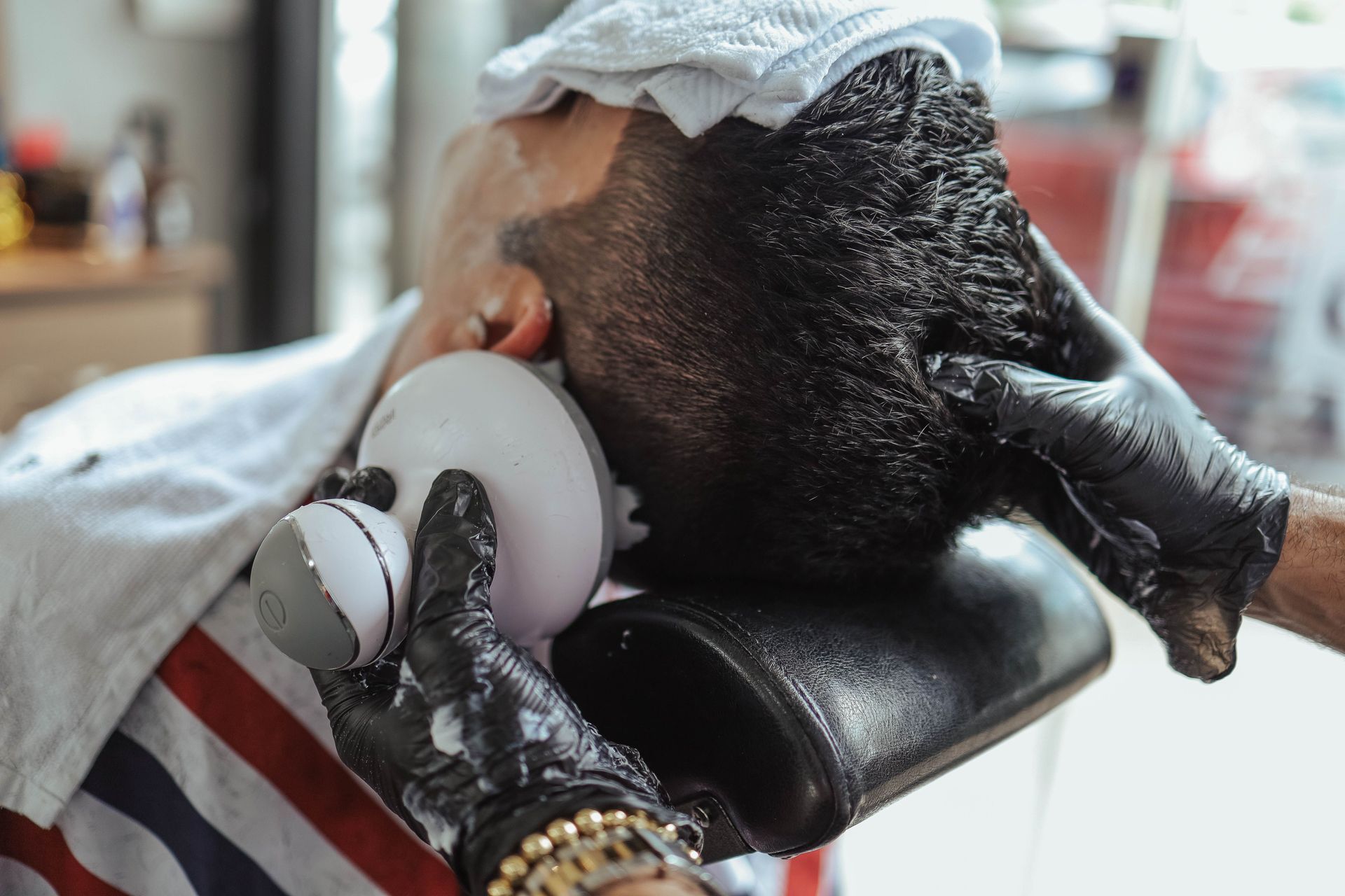 Person receiving a shave with an electric razor at a barber chair