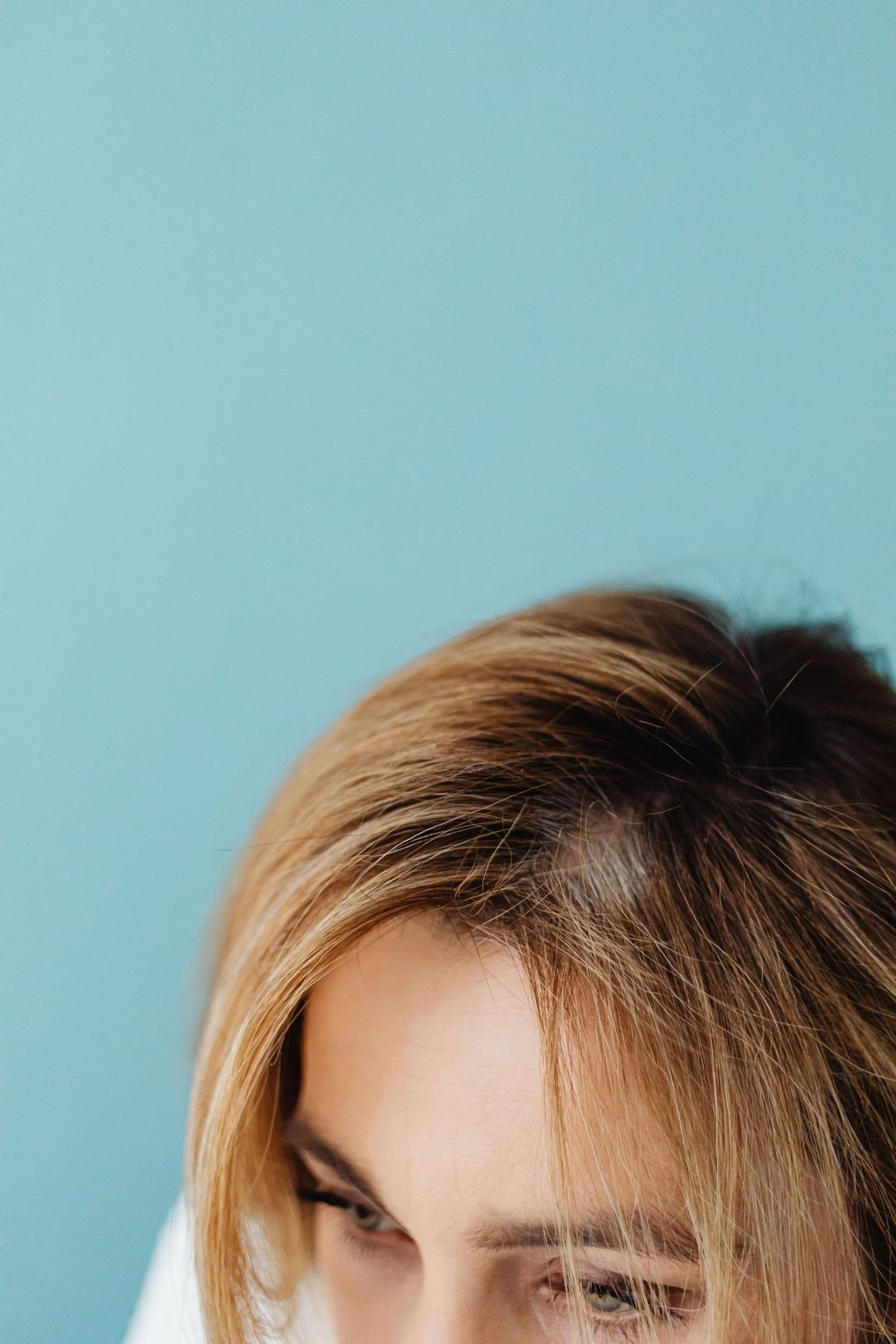 Close-up of a person’s blonde hair and eyes against a light blue background