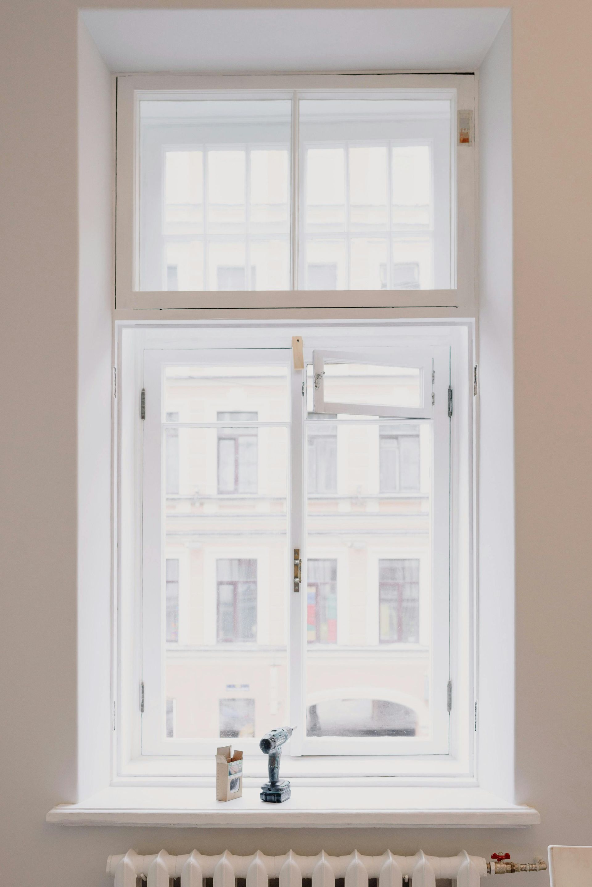 White-framed window in a beige wall with bright daylight and small decorative figurines on the sill